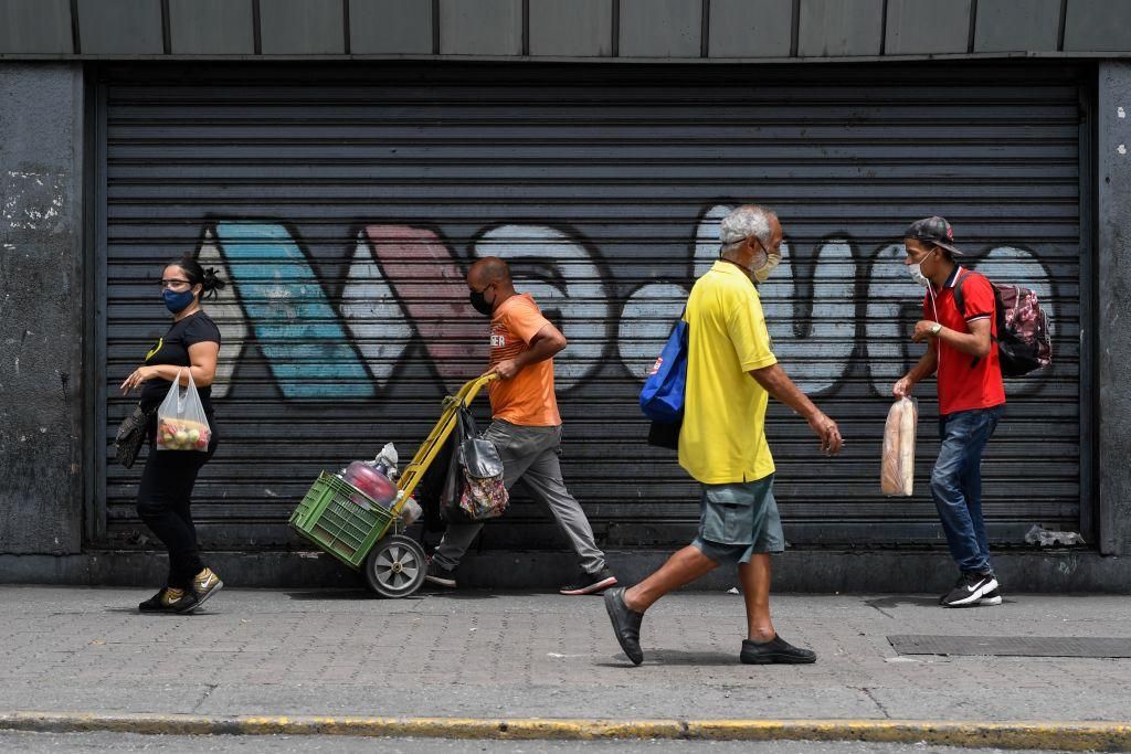 People walk past the metal gate of a closed shop reading "Maduro" in Caracas amid the COVID-19 novel coronavirus pandemic, on September 3, 2020 as inflation increases in Venezuela which is in the midst of the worst economic crisis in its history after seven years of recession. (Photo by Federico PARRA / AFP) (Photo by FEDERICO PARRA/AFP via Getty Images)