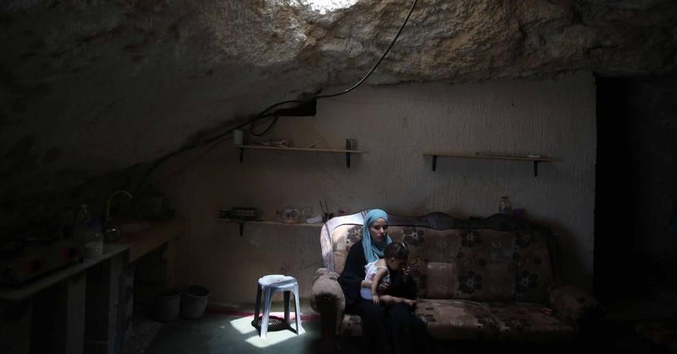 Ahmed Amarne's wife sits on a couch with their daughter inside their cave house in Jenin, West Bank on August 12, 2020. (Photo: Issam Rimawi/Anadolu Agency via Getty Images)