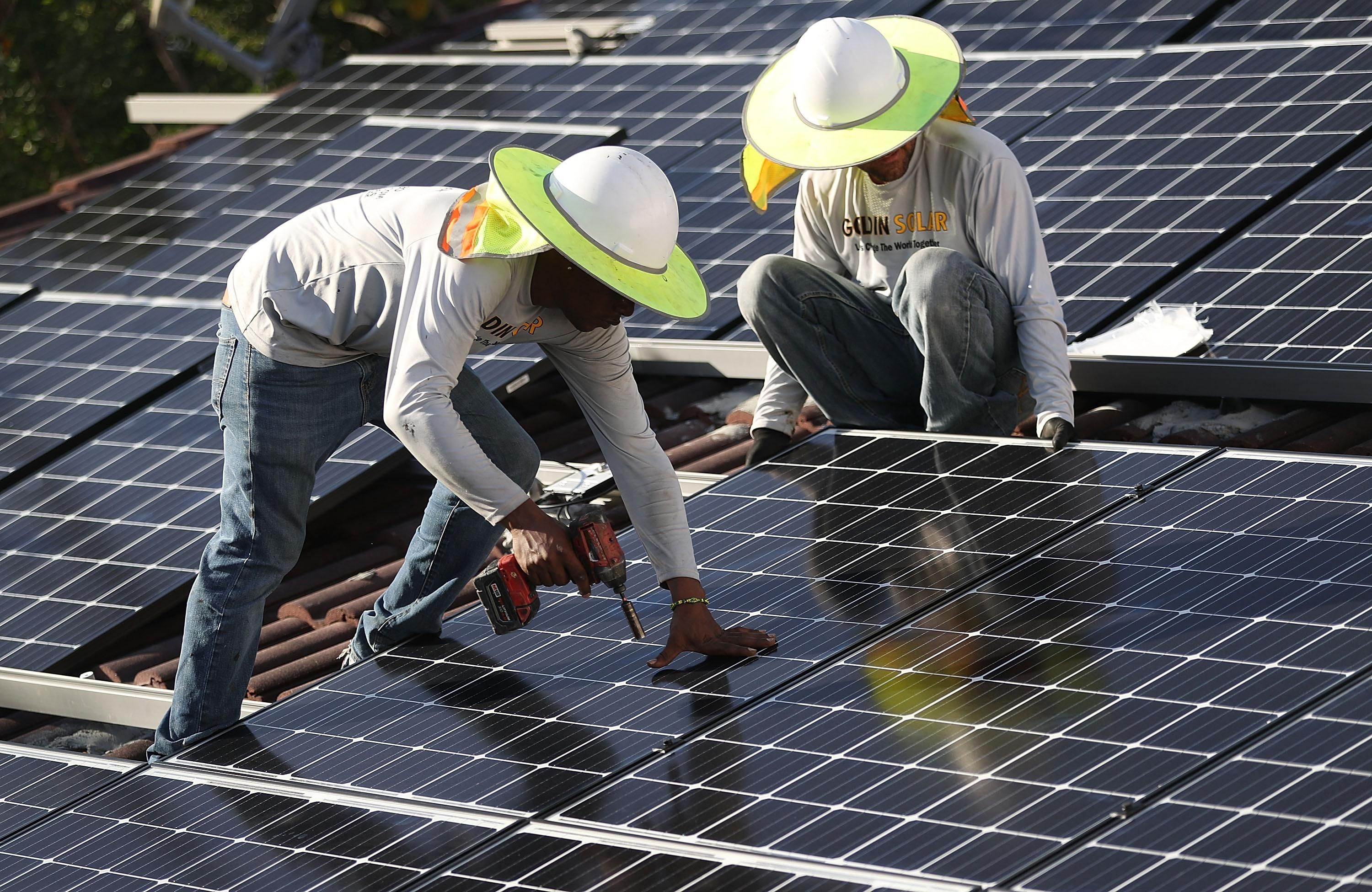 Roger Garbey and Andres Hernandez, from the Goldin Solar company, install a solar panel system on the roof of a home on January 23, 2018 in Palmetto Bay, Florida. (Photo: Joe Raedle via Getty Images)