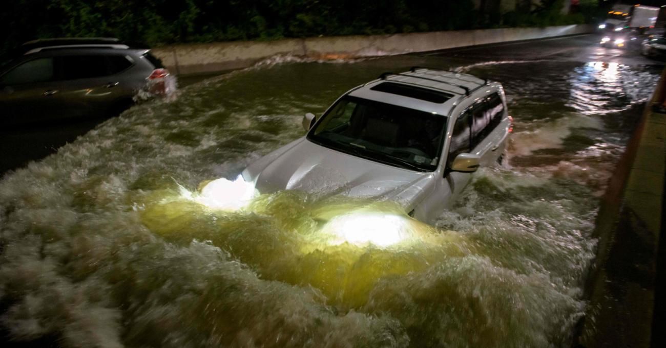 A car drives on a flooded street in New York Cty.