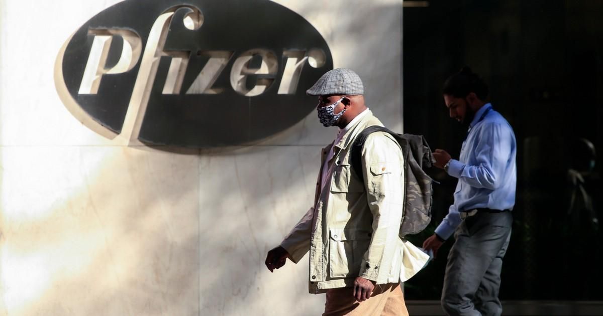 Man walks past Pfizer logo