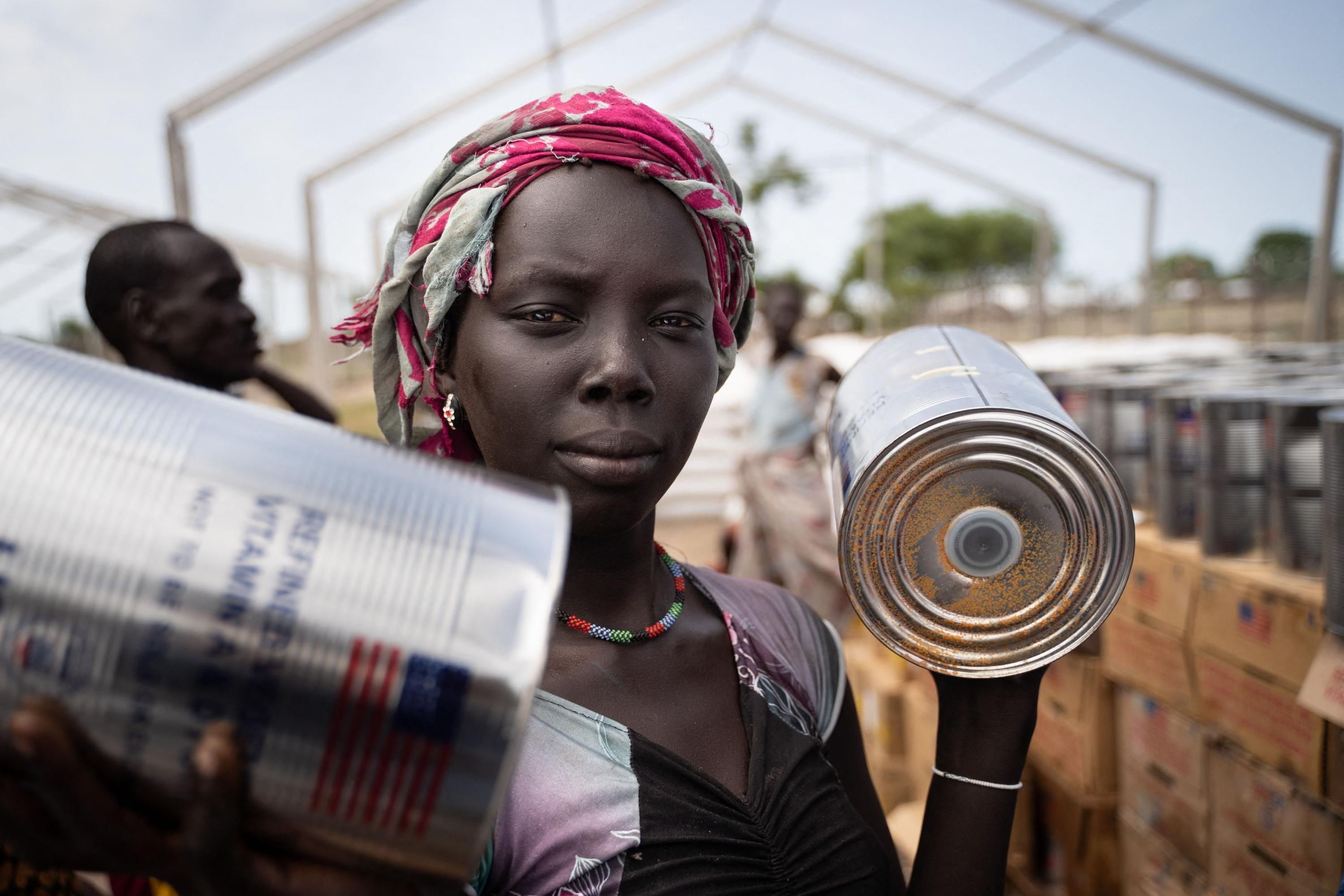 A woman receives cans of oil at a food distribution in South Sudan
