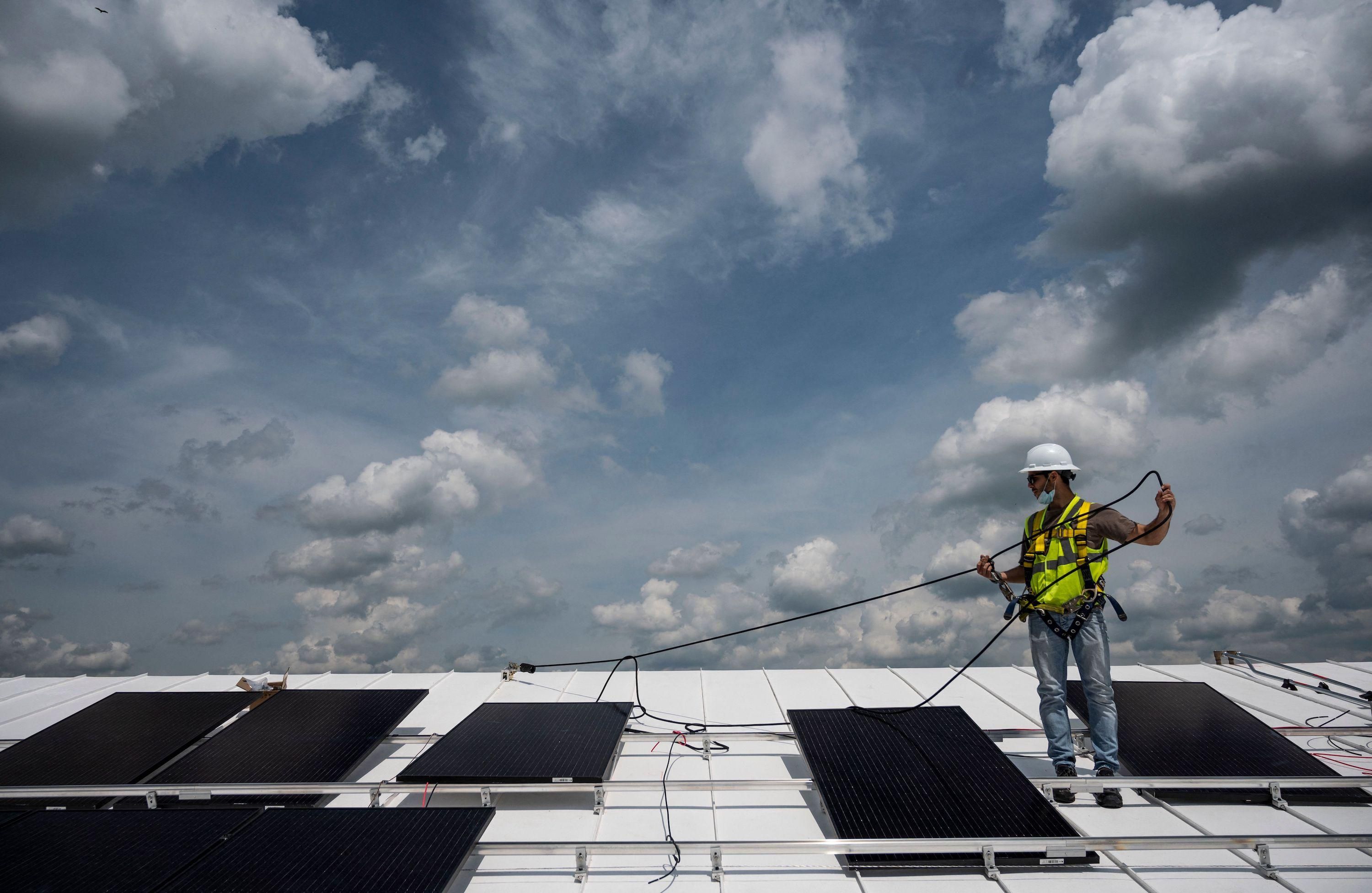An employee with Ipsun Solar installs solar panels on the roof of the Peace Lutheran Church in Alexandria, Virginia on May 17, 2021. 