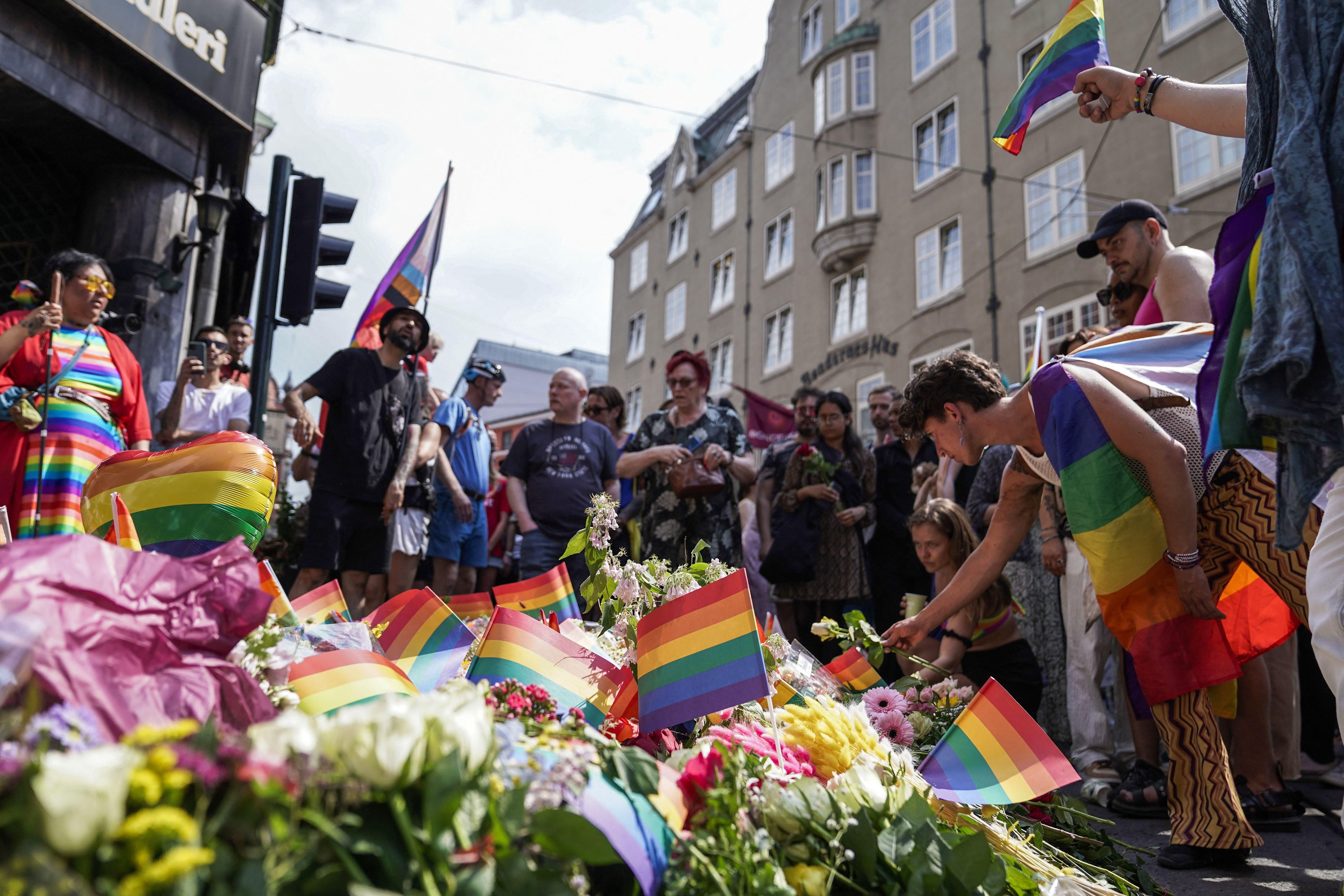 People lay Pride flags and flowers outside the gay bar where a gunman in Oslo killed two people and injured 21 on June 25, 2022.