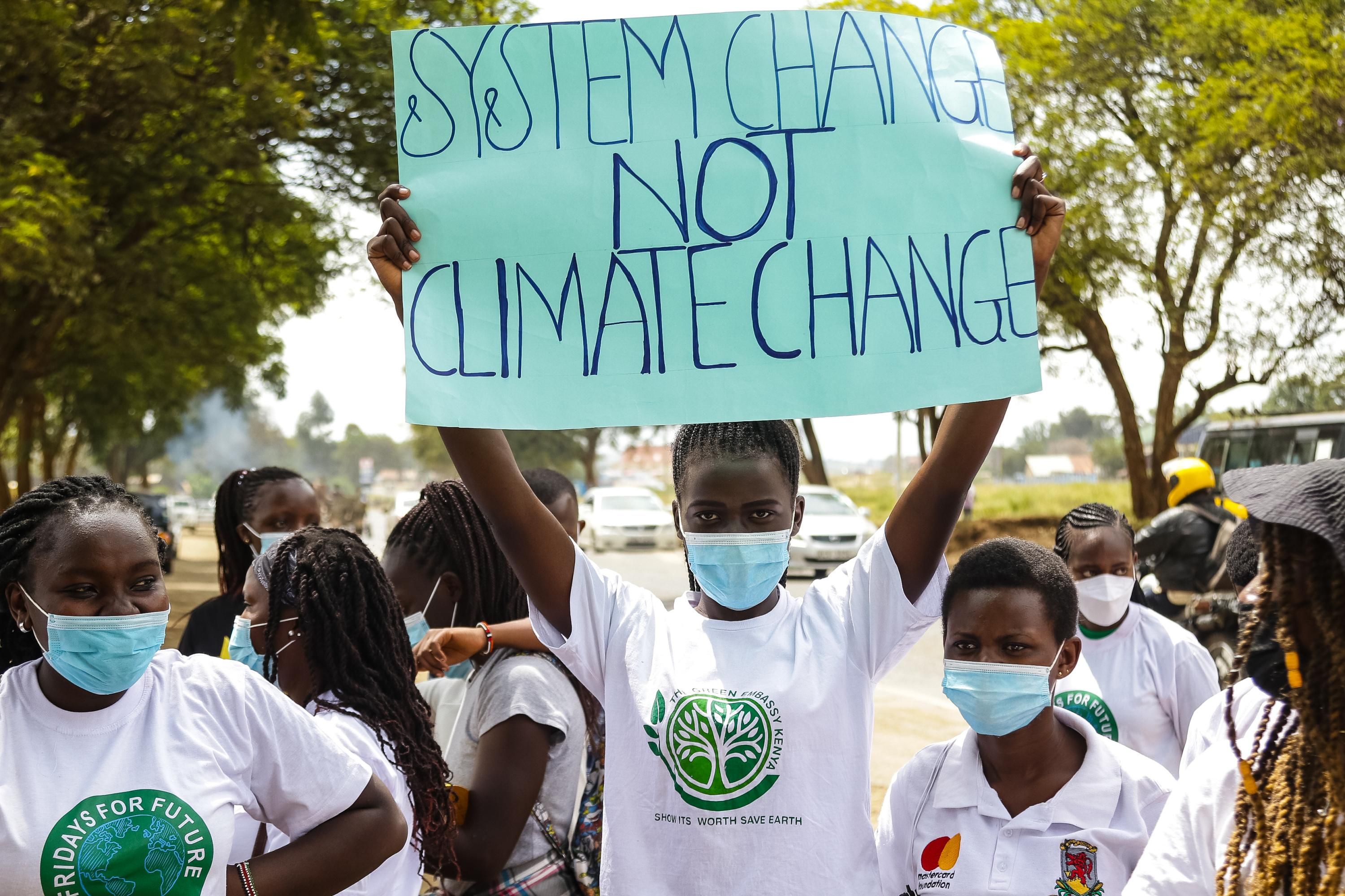 Activist holding sign reading, "System change not climate change"
