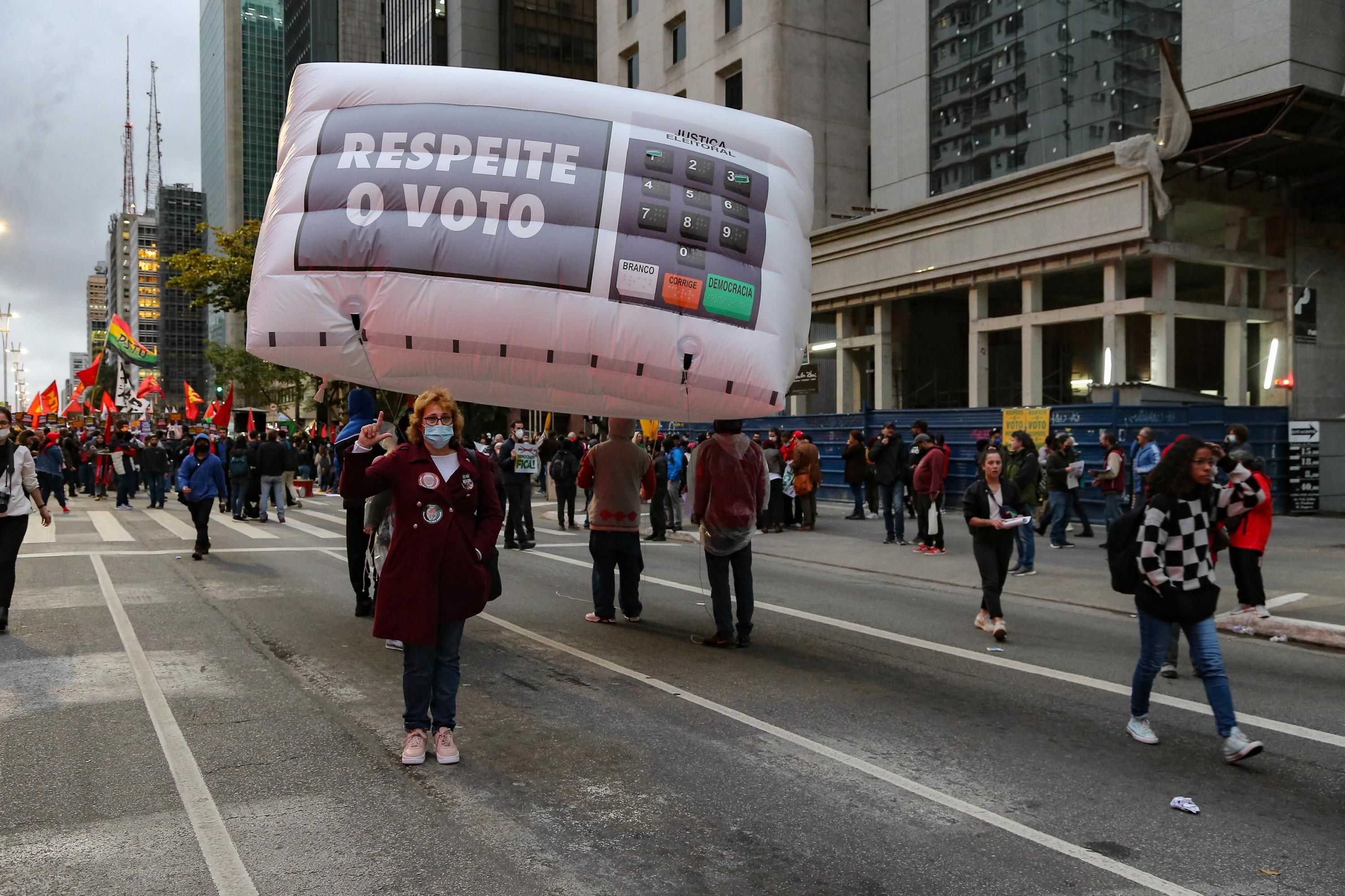 A woman holds sign reading "Respect the Vote in Brazil