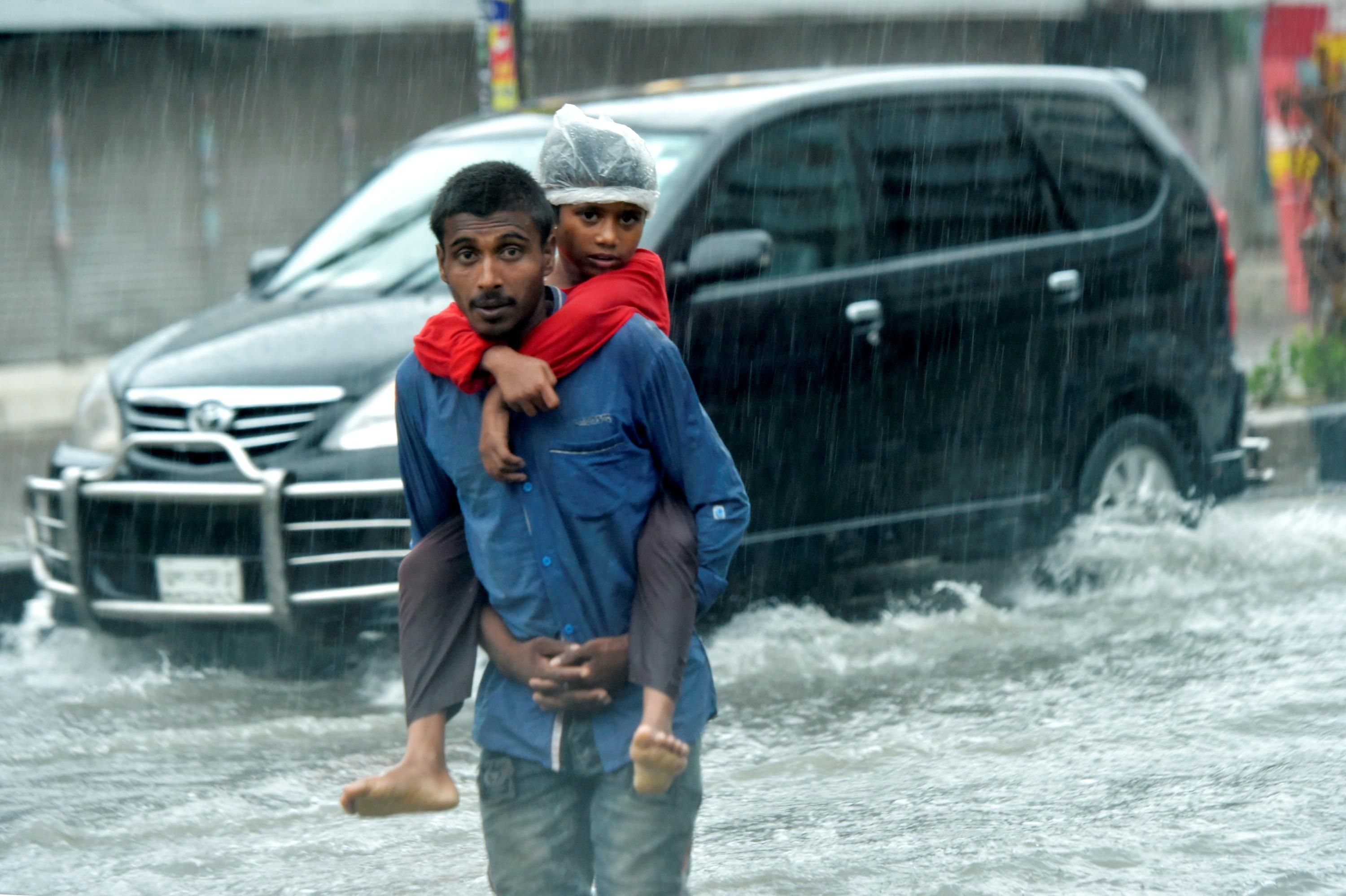 A man and his child attempt to flee a flooding street in Bangladesh