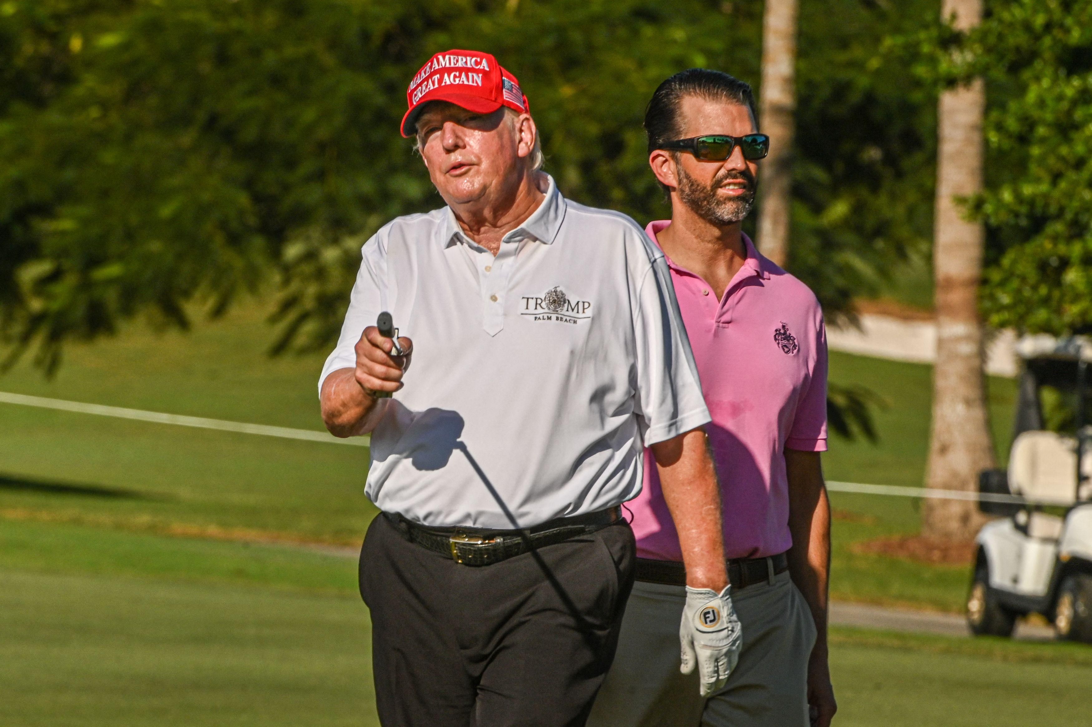 Former U.S. President Donald Trump and his son, Donald Trump Jr., play golf at Trump National Doral Miami golf club on October 27, 2022 in Miami, Florida.
